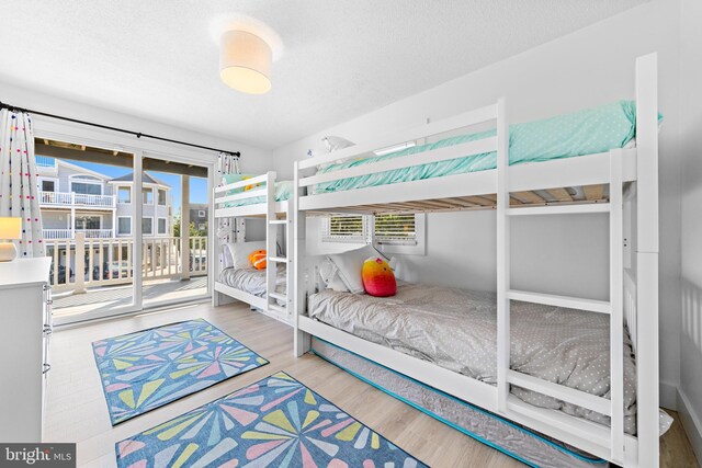 bedroom featuring access to outside, a textured ceiling, and wood-type flooring