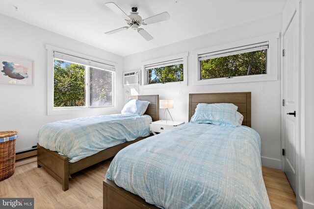 bedroom featuring ceiling fan, a baseboard radiator, light hardwood / wood-style floors, and a wall unit AC