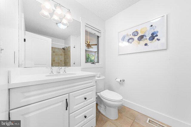 bathroom with vanity, tiled shower, a textured ceiling, tile patterned floors, and toilet