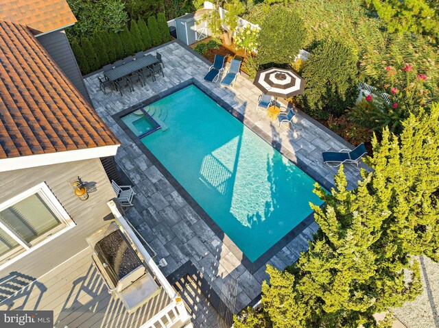 view of swimming pool with a patio, a storage unit, and an outdoor fire pit