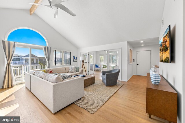 living room featuring light wood-type flooring, beam ceiling, ceiling fan, and high vaulted ceiling