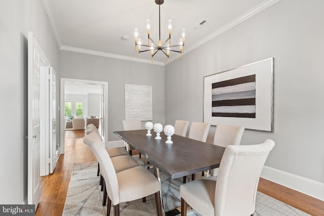 dining room featuring crown molding, a notable chandelier, and light hardwood / wood-style flooring