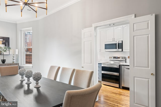 dining space featuring light wood-type flooring, an inviting chandelier, and ornamental molding