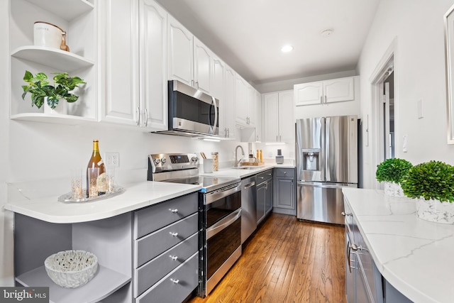 kitchen with white cabinets, gray cabinetry, stainless steel appliances, light hardwood / wood-style floors, and sink