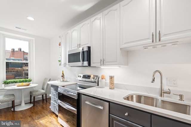 kitchen with light stone counters, sink, dark wood-type flooring, appliances with stainless steel finishes, and white cabinets