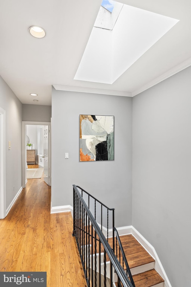 hall with a skylight and light hardwood / wood-style flooring