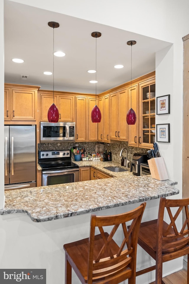 kitchen featuring decorative light fixtures, stainless steel appliances, sink, tasteful backsplash, and a breakfast bar