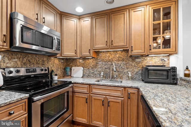 kitchen featuring sink, light stone countertops, appliances with stainless steel finishes, and tasteful backsplash