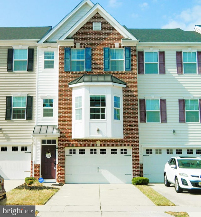 multi unit property featuring a garage, driveway, a standing seam roof, metal roof, and brick siding