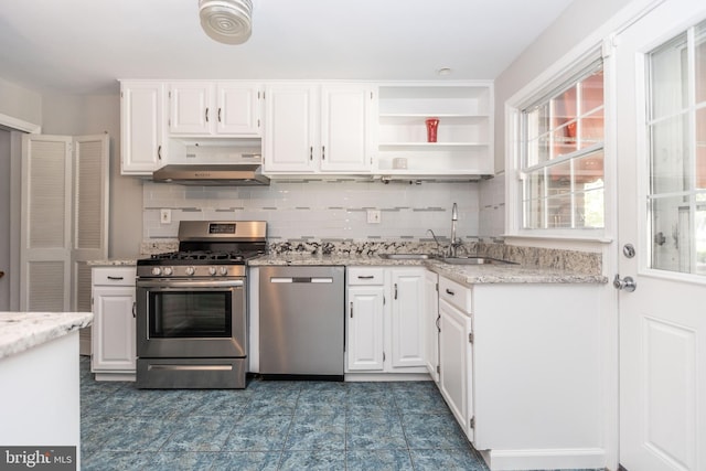 kitchen featuring light stone counters, backsplash, white cabinetry, exhaust hood, and appliances with stainless steel finishes