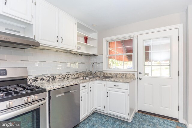 kitchen featuring tasteful backsplash, sink, white cabinets, appliances with stainless steel finishes, and light stone countertops