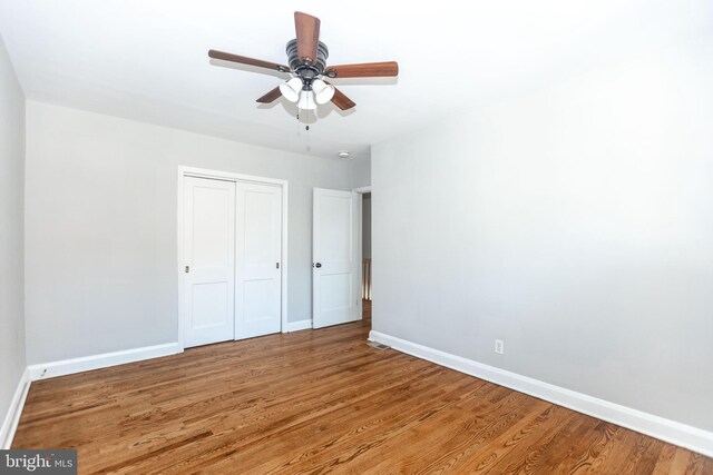 unfurnished bedroom featuring wood-type flooring, a closet, and ceiling fan