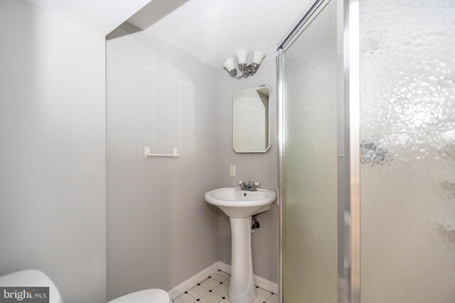 bathroom featuring a shower with door and toilet