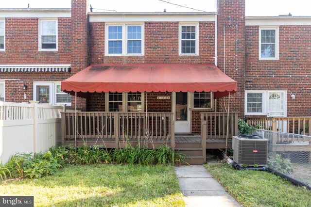 view of front of property featuring cooling unit, a wooden deck, and a front yard