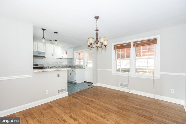 kitchen featuring a chandelier, hardwood / wood-style flooring, white cabinetry, hanging light fixtures, and backsplash