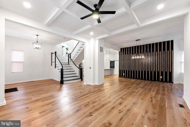 unfurnished living room featuring a healthy amount of sunlight, light hardwood / wood-style floors, and coffered ceiling