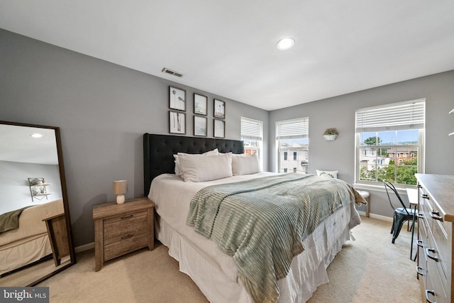 bedroom with visible vents, light carpet, and baseboards