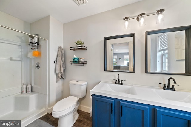 full bath featuring toilet, wood finished floors, visible vents, double vanity, and walk in shower