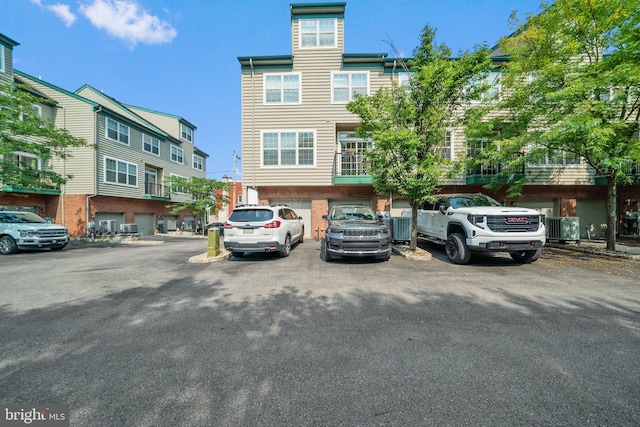 view of front facade with uncovered parking, cooling unit, and brick siding