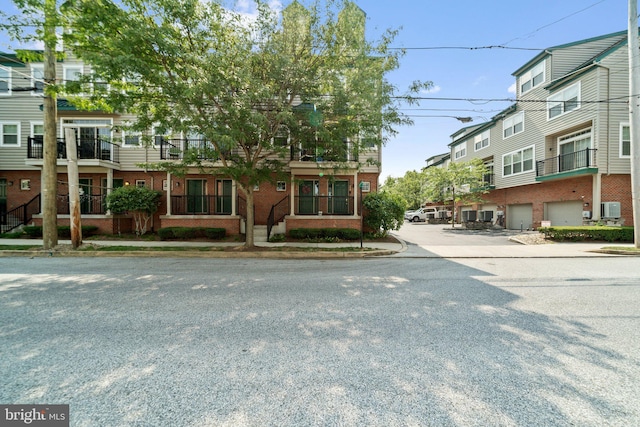 exterior space with a garage, a residential view, brick siding, and driveway