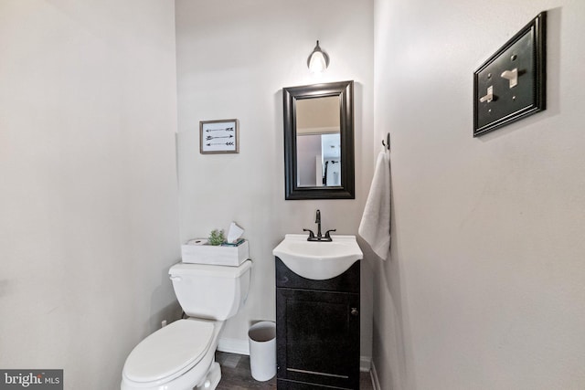 bathroom featuring toilet, baseboards, and vanity