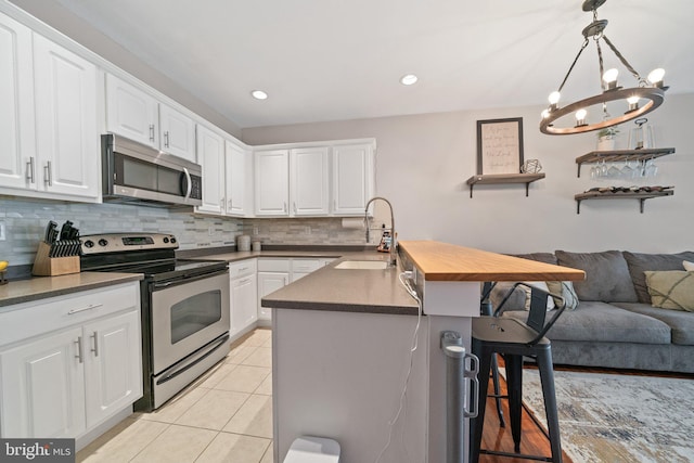 kitchen with a sink, stainless steel appliances, a kitchen bar, backsplash, and light tile patterned flooring