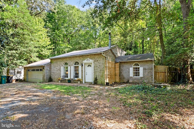 view of front of house with an attached garage, fence, brick siding, and driveway