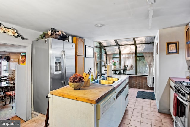 kitchen featuring light tile patterned floors, an island with sink, stainless steel appliances, sink, and wooden counters