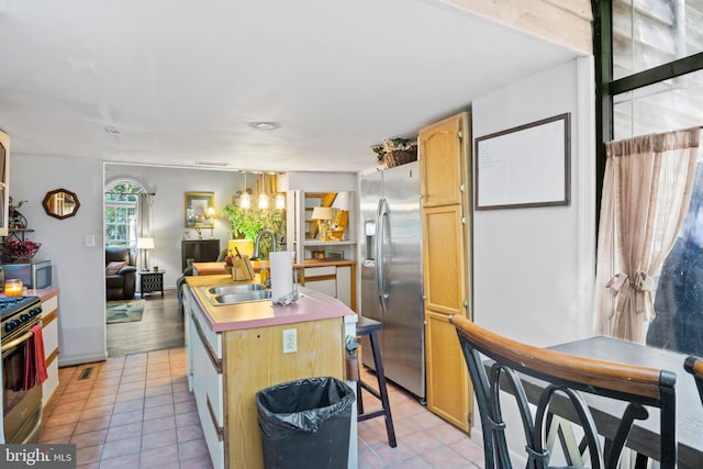 kitchen featuring light brown cabinetry, light tile patterned floors, appliances with stainless steel finishes, sink, and a kitchen island