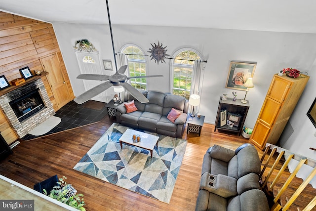 living room featuring ceiling fan, hardwood / wood-style floors, high vaulted ceiling, and a fireplace