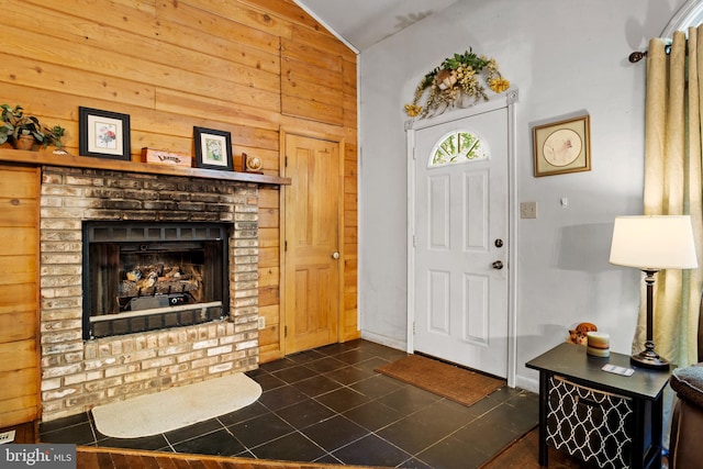 tiled entryway with a fireplace, vaulted ceiling, and wooden walls