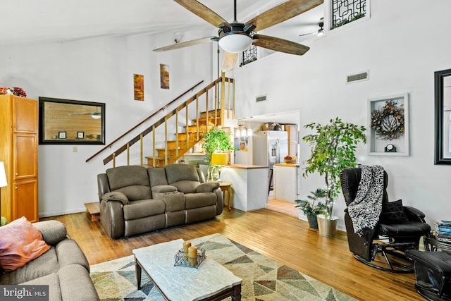 living room with high vaulted ceiling, ceiling fan, and light hardwood / wood-style floors