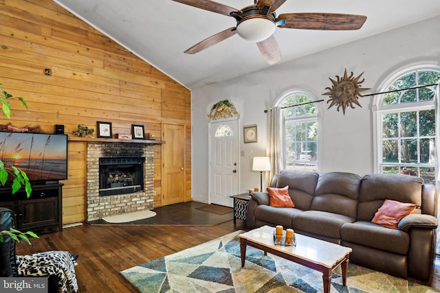 living room featuring a fireplace, dark wood-type flooring, plenty of natural light, and wooden walls