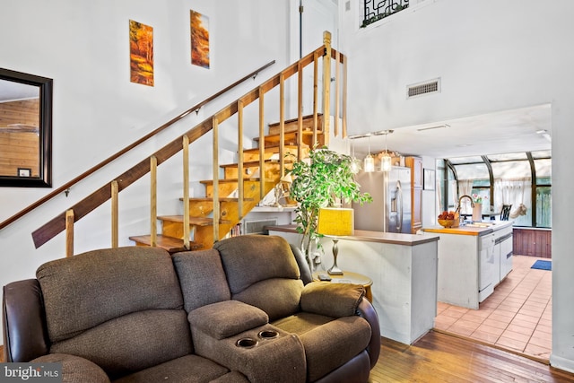 interior space featuring visible vents, light wood-style flooring, stairs, and a high ceiling