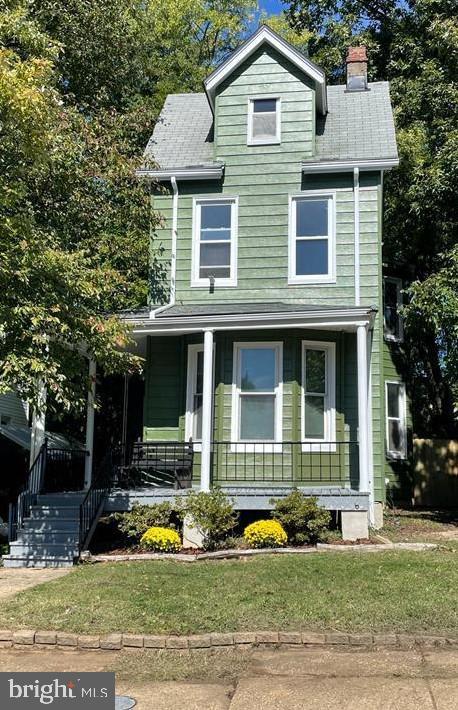 american foursquare style home with a porch and a chimney