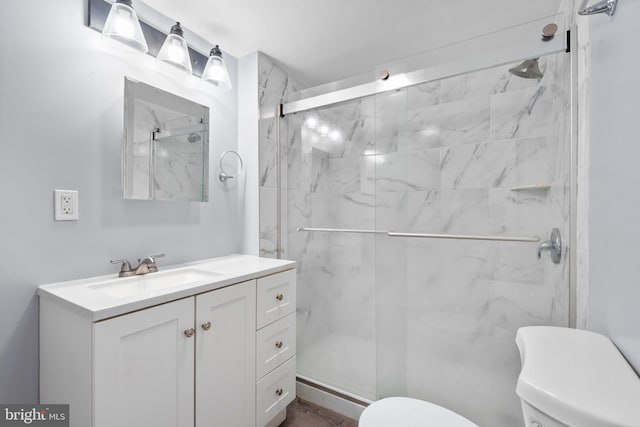 bathroom with a marble finish shower, vanity, and toilet