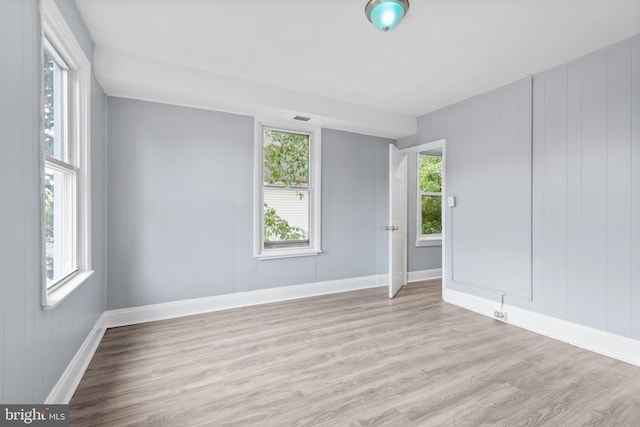 spare room with baseboards and wood finished floors