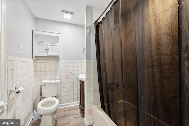 full bathroom featuring tile walls, shower / bathtub combination with curtain, toilet, wainscoting, and wood finished floors