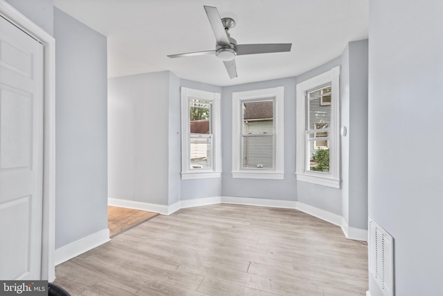 empty room with light wood-style flooring, visible vents, ceiling fan, and baseboards