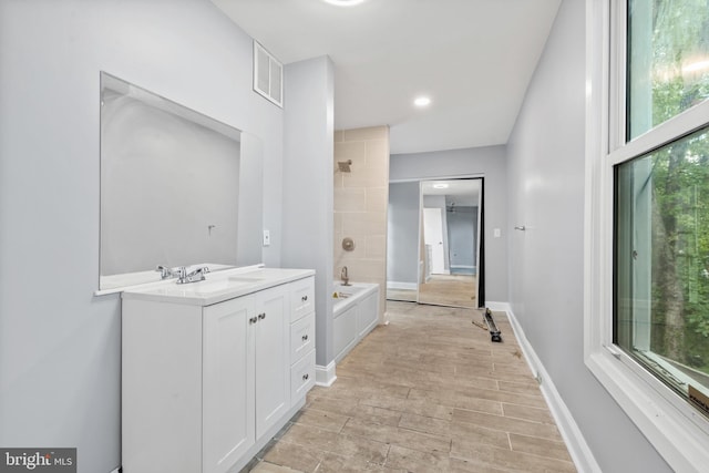 full bath featuring visible vents, tub / shower combination, baseboards, wood finished floors, and vanity