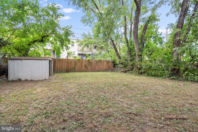 view of yard featuring an outbuilding, fence, and a storage shed