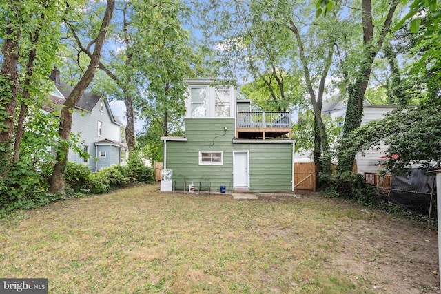 rear view of property with a balcony, a lawn, fence, and a gate