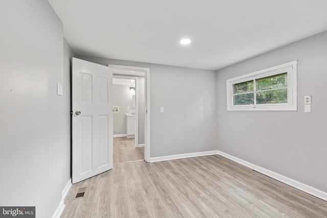 spare room featuring visible vents, light wood-style flooring, and baseboards