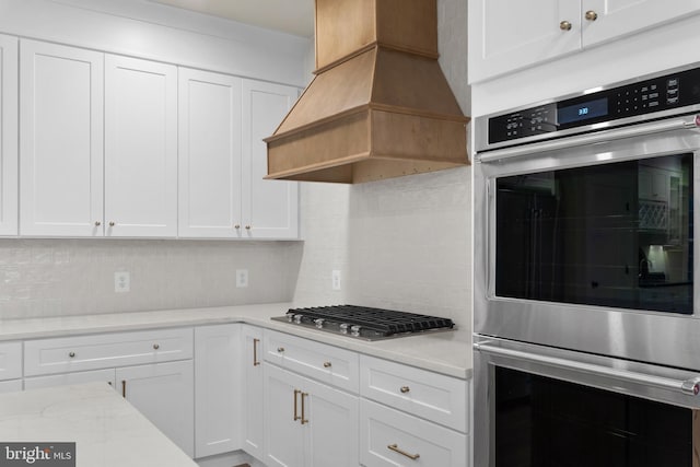 kitchen featuring appliances with stainless steel finishes, backsplash, white cabinets, and custom range hood