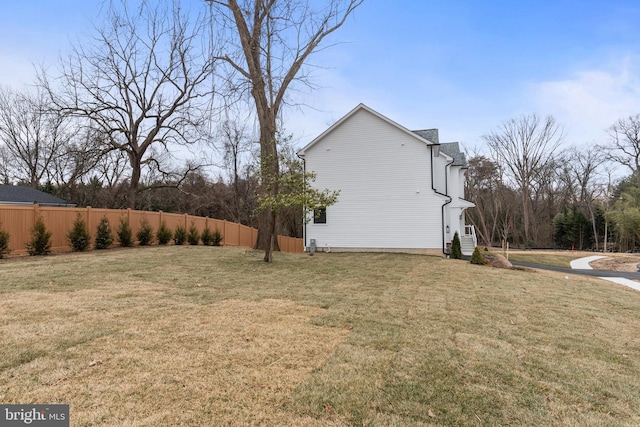 view of side of home featuring fence and a lawn