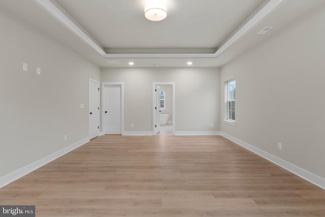 spare room featuring baseboards, a tray ceiling, recessed lighting, and light wood-style floors