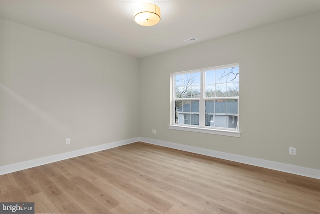 empty room featuring light wood-type flooring, visible vents, and baseboards