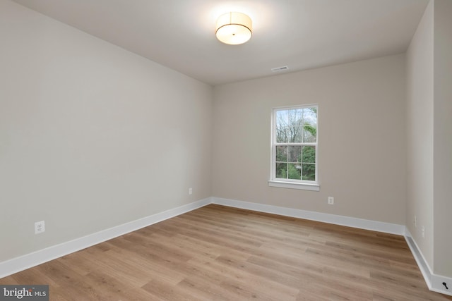 unfurnished room with light wood-style floors, visible vents, and baseboards