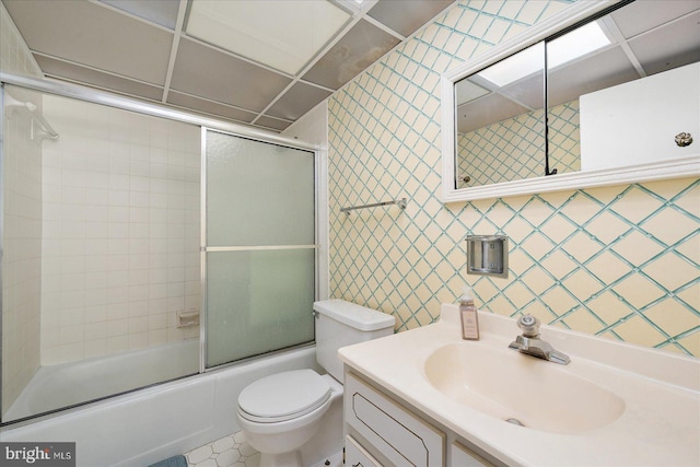 full bathroom with wallpapered walls, toilet, vanity, and shower / bath combination with glass door