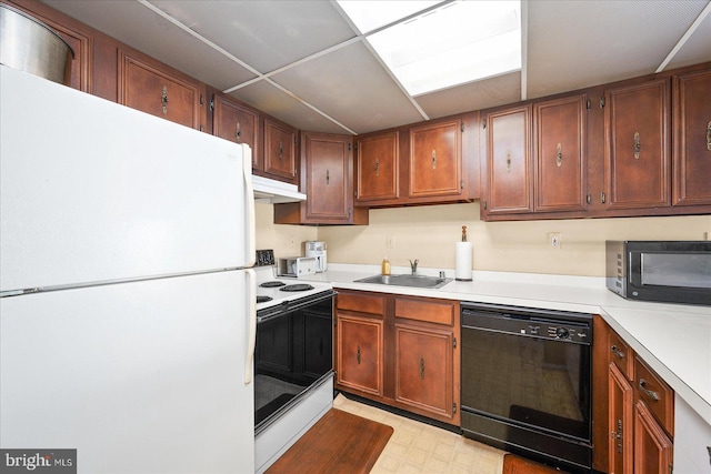 kitchen with light floors, a paneled ceiling, a sink, light countertops, and black appliances